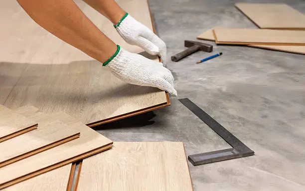 Crew performing laminate flooring installation inside a Liberty Lake - WA home while checking plank alignment, Installer measuring laminate flooring installation details inside a Hayden - ID home before securing final edge pieces