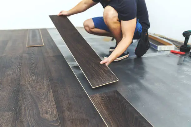 Installer completing laminate flooring installation in a Coeur d'Alene - ID home while checking board spacing